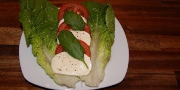 Anret tomatsalaten flot på en tallerken med hjertesalat og mozzarella.