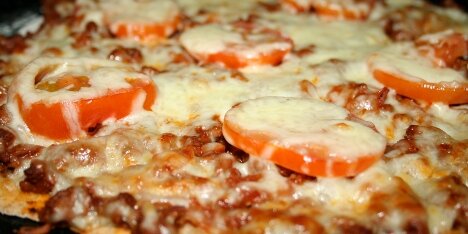 Pizza med oksekød, løg, tomat og ost.