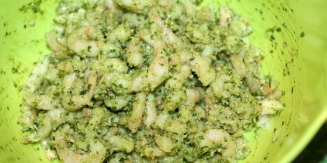 Rejer og pesto balndes sammen i en skål.