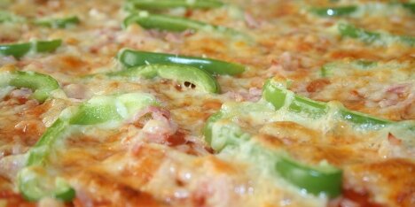 Pizza med skinke, grøn peber og mozarellaost.
