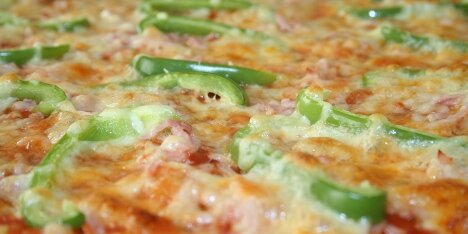 Pizza med skinke, grøn peber og mozarellaost.