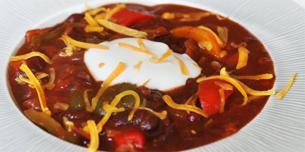 Chili sin carne serveret med en klat creme fraiche og cheddar på toppen.