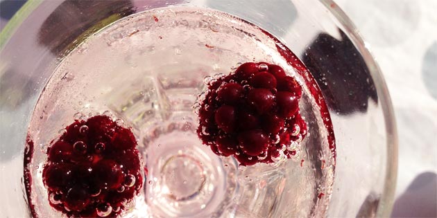 Ekstra dekorativ bliver velkomstdrinken toppet med røde hindbær.