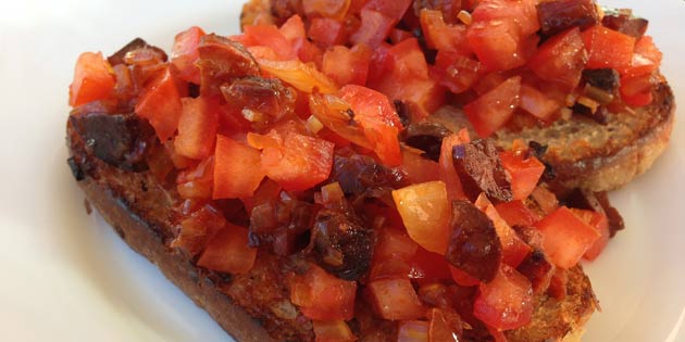 De færdige bruschettas, serveringsklar med fyld af chorizo og saftig tomat.