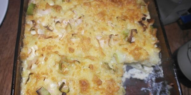 Indbydende kartoffelgratin med grønne porrer og en gylden overflade.
