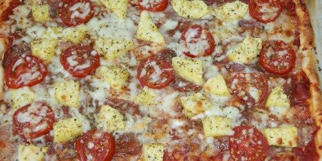 En lækker Hawaii pizza med ananas, skinke, ost og tomater.