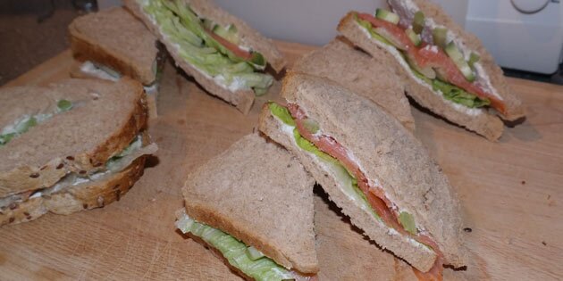 Laksens lyserøde kulør og den grønne salat titter indbydende frem fra sandwichen.