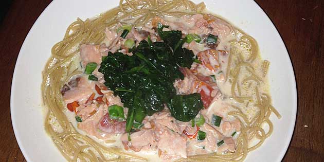Den grønne spinat og lyserøde fisk pynter på spaghettien.