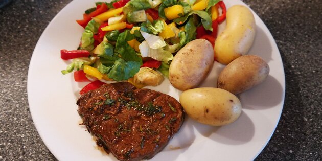 De italiensk marinerede bøffer er her serveret med kartofler og farverig salat.