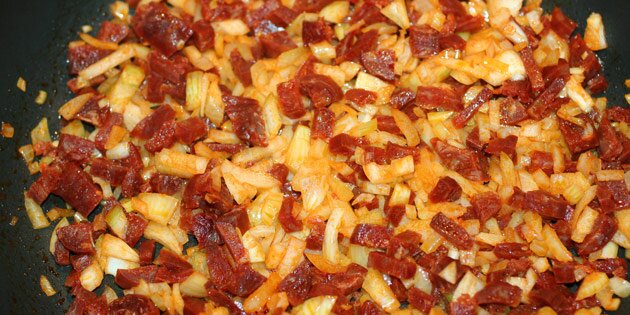 Chorizoen giver både smag og farve til løgene.