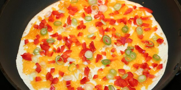 Ost og grøntsager kommes på en pandekage.