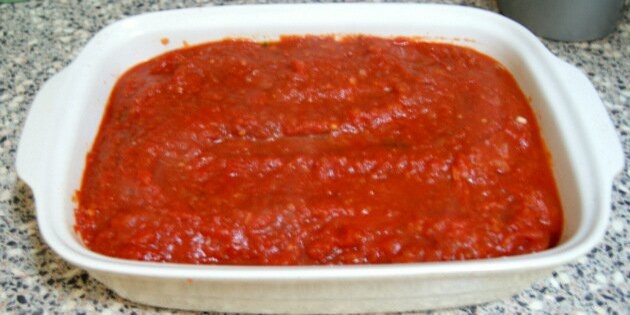 Det hele overhældes med tomatsovs, inden det kommes i ovnen.
