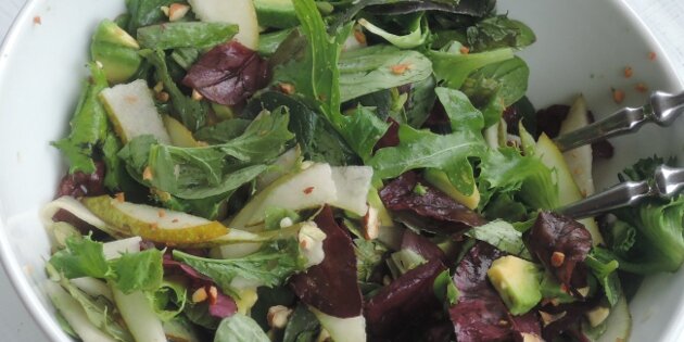 Pærestykker og avocado kan ses i de friske salatblade