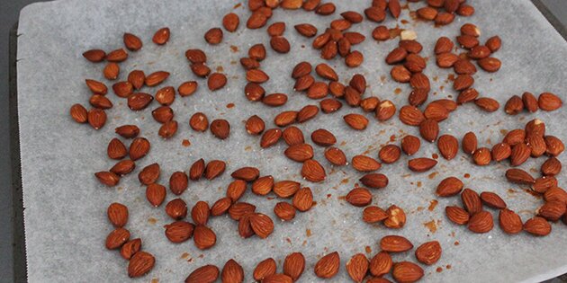 De våde mandler hældes ud på et stykke bagepapir.