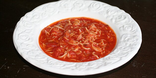 En portion tomatsuppe med stykker af nudler