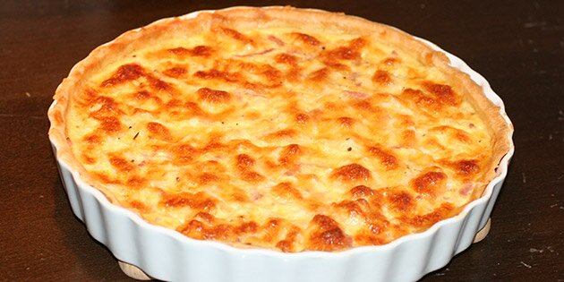 Et styks blomkålstærte med skinke og smeltet ost på toppen.