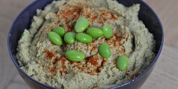 Cremet edamamehummus drysset med paprika og edamamebønner på toppen.