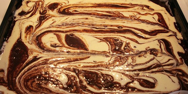 Her er flødeostcremen fordelt udover chokoladekagen, og der er lavet hvivler med en gaffel.