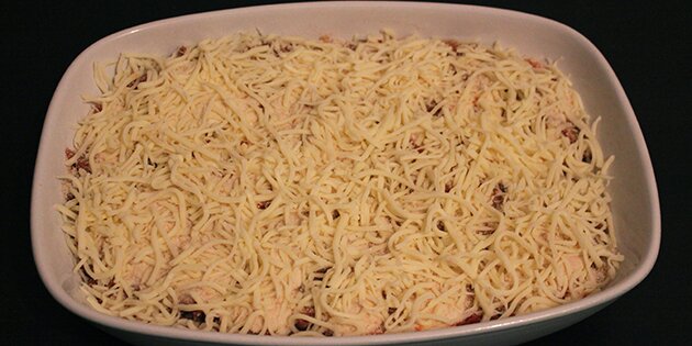 Toppet med rasp og revet ost, der giver en sprød skorpe.