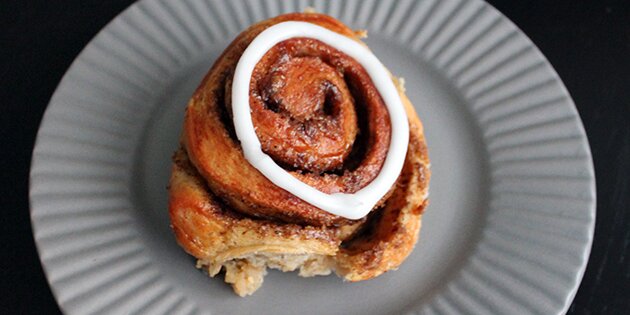 En lækker kanelsnegl, der er skåret fra den snaskede kage.