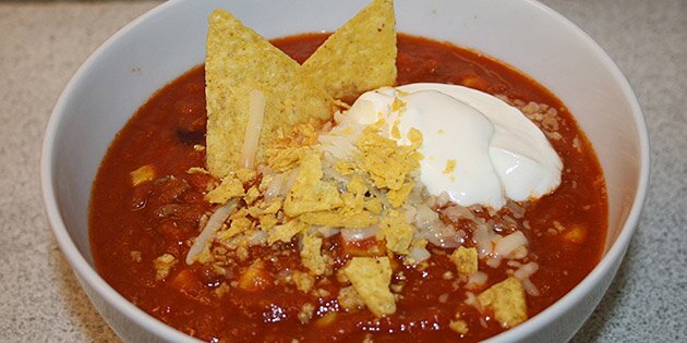 En portion dejlig tacosuppe med knuste tortillachips og creme fraiche