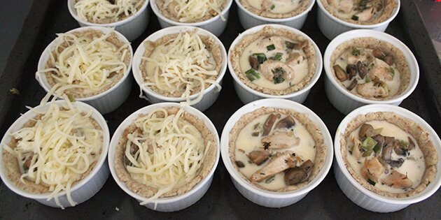 Her er tærterne fyldt med fyldet og halvdelen er toppet med ost.