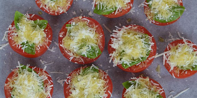 De halve tomater toppes med parmesan og basilikum eller andre krydderurter efter smag.