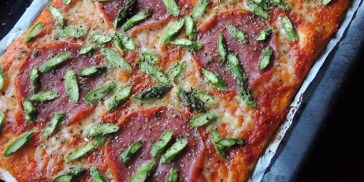 Sprød pizzabund med tomatsauce, smeltet ost og topping