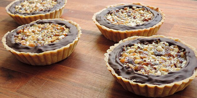 De friskbagte små nøddetærter pyntes med mørk chokolade