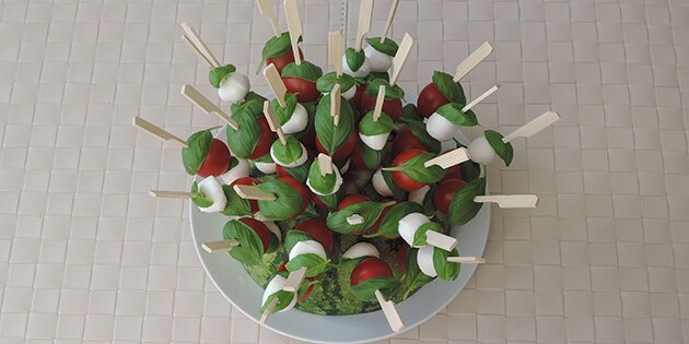 Vandmelon-pindsvinet er lavet med spyd fyldt med små tomater, kugler af mozzarella og frisk basilikum