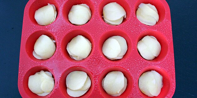 Læg lag af kartofler, løg, hvidløg, salt og smør, indtil formene er fyldt.