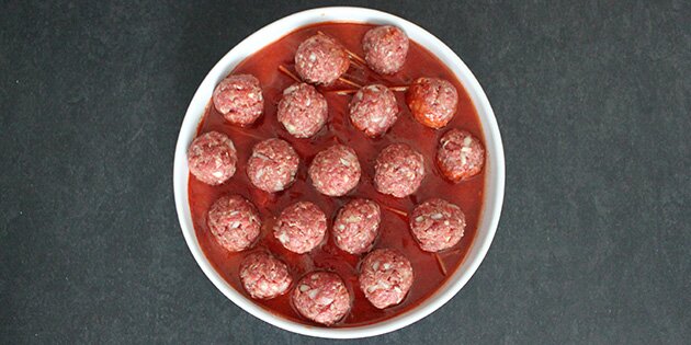Her er kødbollerne formet og placeret i tomatsaucen.