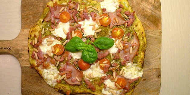 Den sprøde pizzabund får selskab af lækre pinjekerner og en herlig pesto.