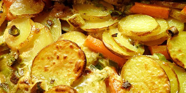 Kartoflerne og gulerødderne bages i ovnen med fløde og forårsløg.