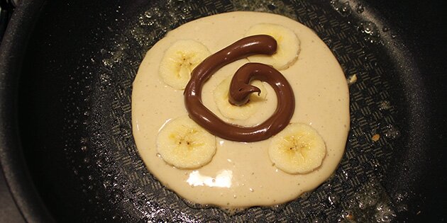 Hæld lidt dej på panden, fyld Nutella og banan ovenpå, og luk så pandekagerne med mere dej.
