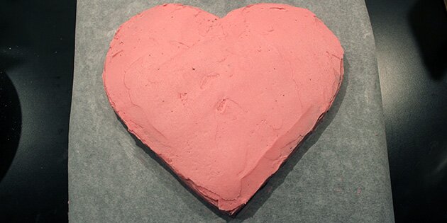 Fordel smørcremen på kagen, så den ligner et flot, lyserødt hjerte.