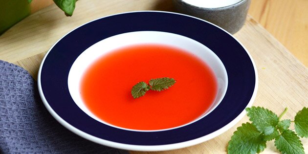 Den kolde jordbær-rabarbersuppe smager perfekt serveret med vaniljeis og flødeskum.