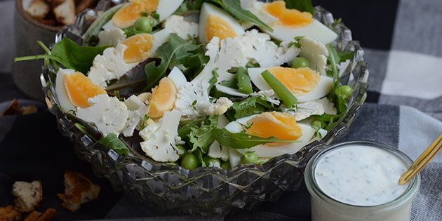 De hårdkogte æg, den fintsnittede blomkål og de friske grøntsager skaber en fyldig og mættende salat.