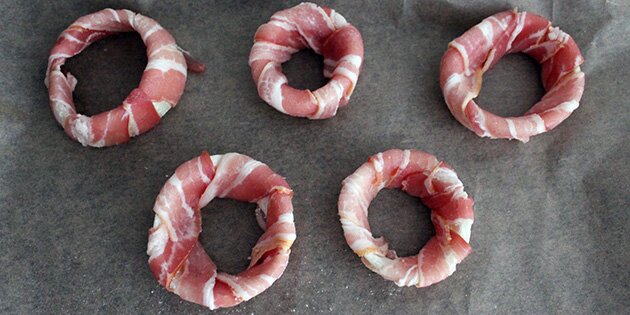 Vikl bacon rundt om løgringene, og bag dem i ovnen.