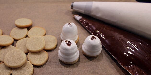 Sprøjt marengsen ud på bundene, og fyld så karamel i midten.