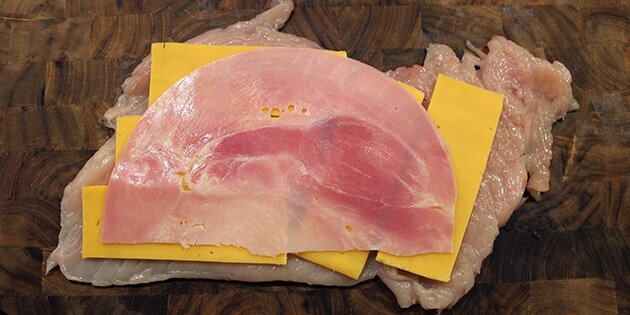 Læg skinke og ost i kyllingen, så den får den berømte kerne af smeltet ost og skinke. Mums!