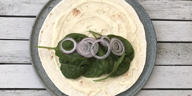 En smurt tortillapandekage med spinat og rødløg.