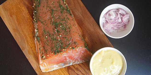 Servér den delikate laks med sennepsdressing og friske rødløg