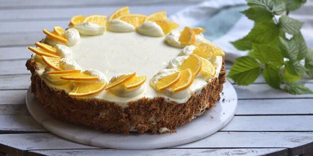 Pynt kagen fint med flødeostecreme og små appelsinstykker.