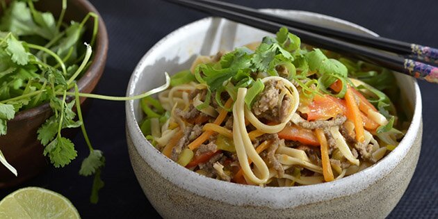 Server nudelretten med friske forårsløg og koriander på toppen samt lidt ekstra lime.