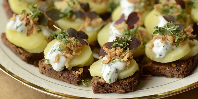 De fine små stykker smørrebrød med kartoffel, purløgsmayo og ristede løg.