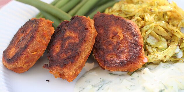 Her er de serveret med raita, kogte bønner og stegt spidskål med karry.