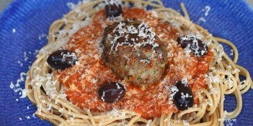 Her er tomatsovs og pasta serveret med oliven, italienske frikadeller og friskrevet parmesan.