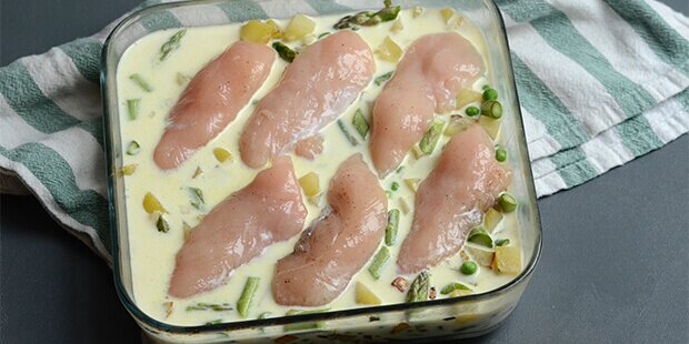 Sovsen hældes over, og de krydrede kyllingefileter lægges ovenpå - så er det i ovnen igen.