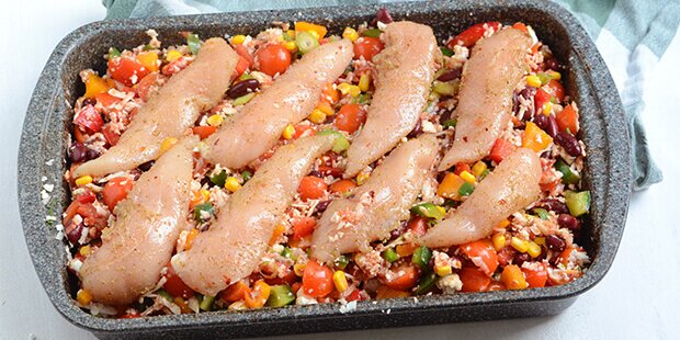 Når kyllingeinderfileterne er krydrede, lægges de ovenpå grøntsagerne i fadet.